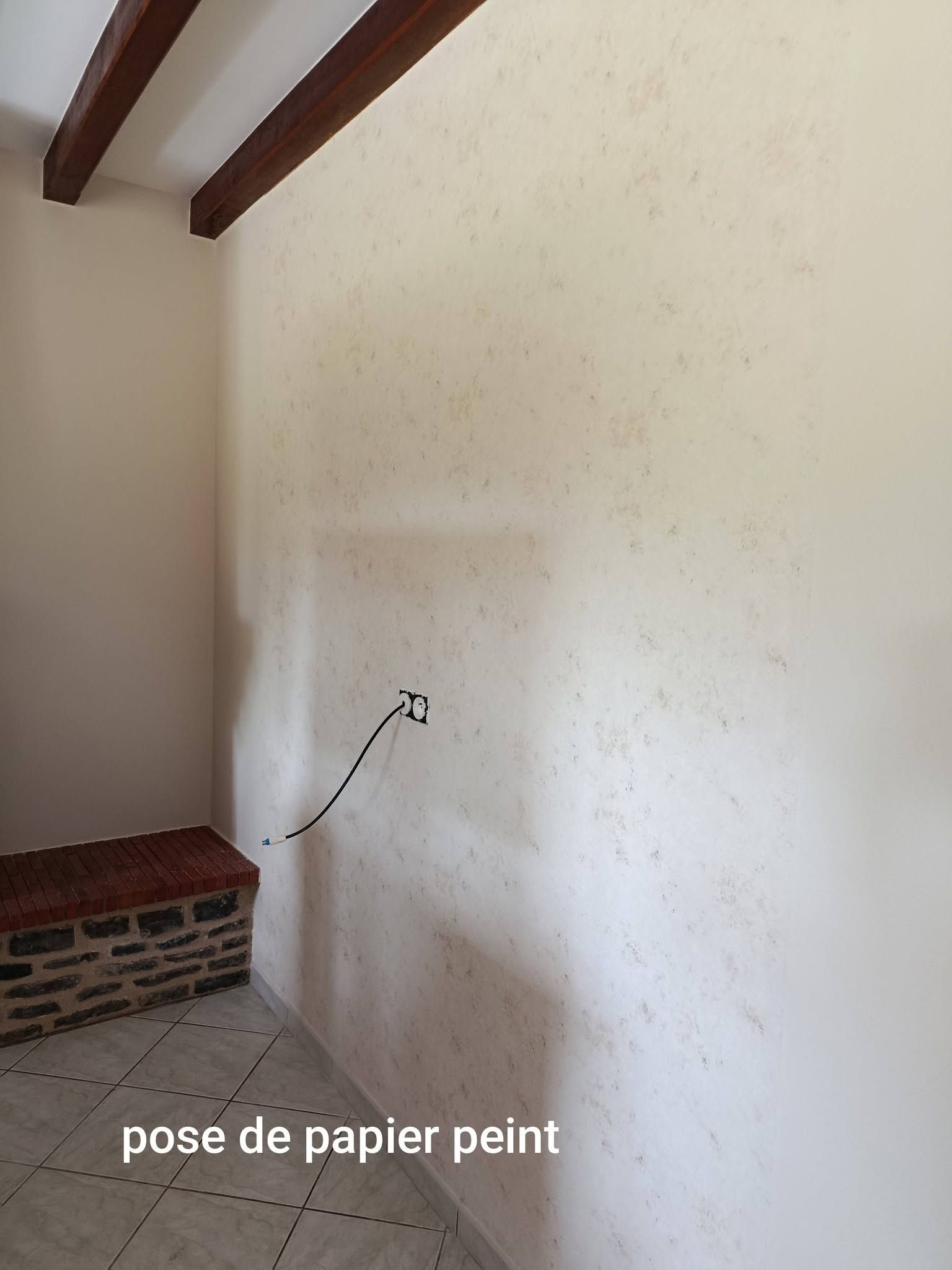 Un mur avant rénovation, avec des poutres apparentes au plafond.