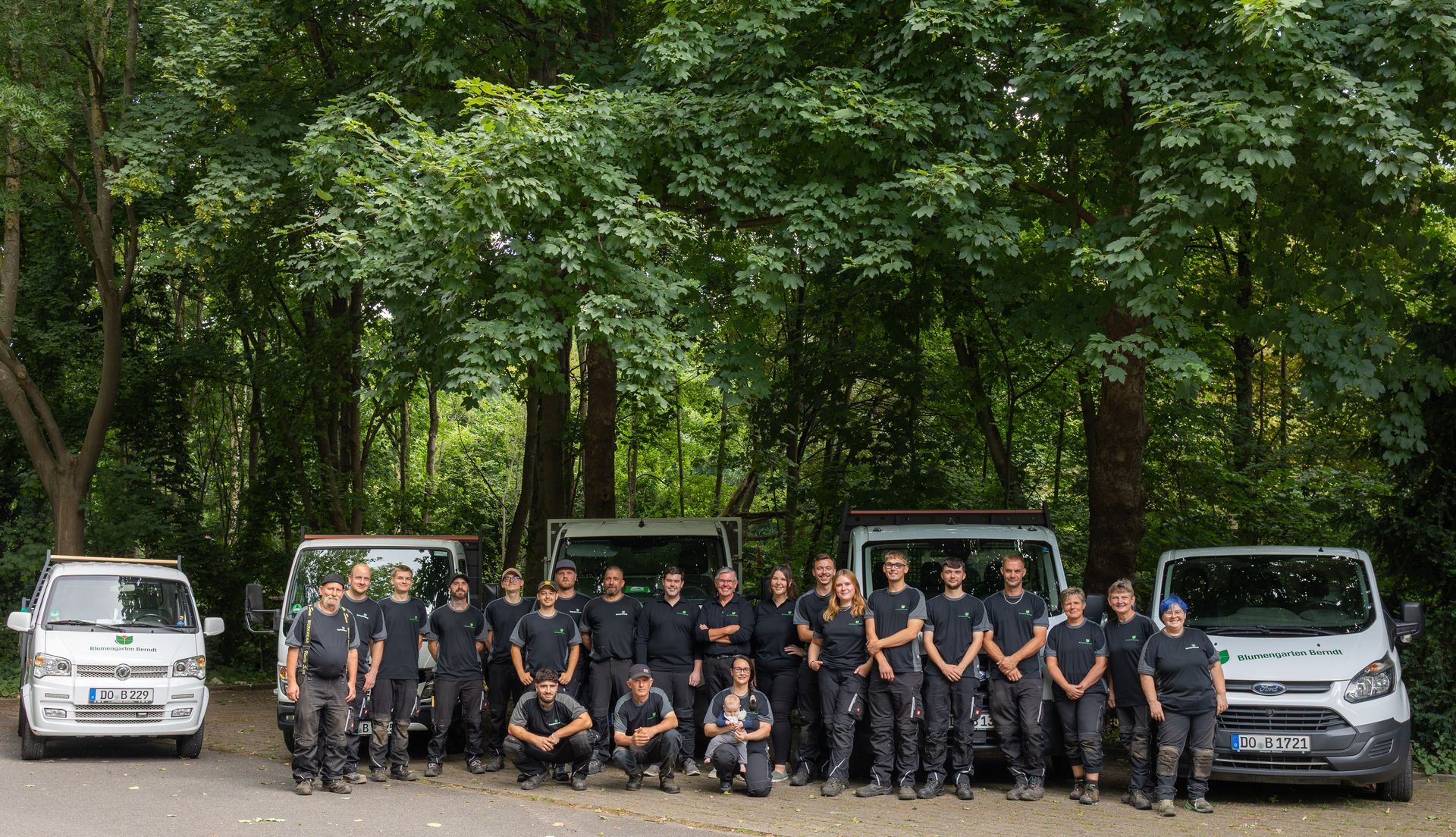 Ein Teamfoto der Blumengarten Berndt KG vor ihren Fahrzeugen in einem Waldgebiet