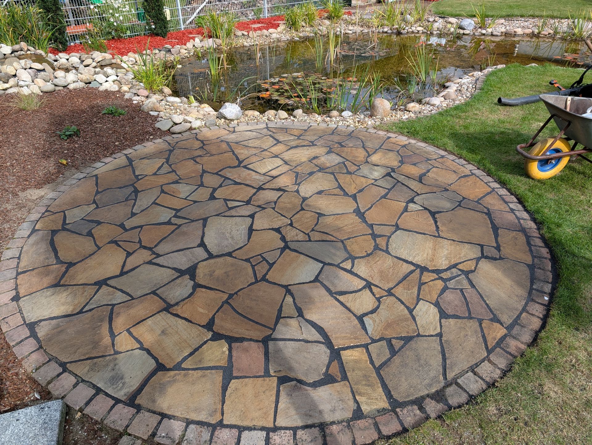 Runder Steinhof mit Zierteich und Garten im Hintergrund