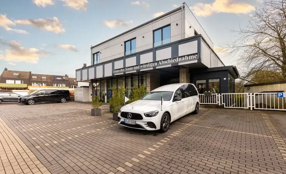 Ein weißes Auto parkt vor einem Gebäude.