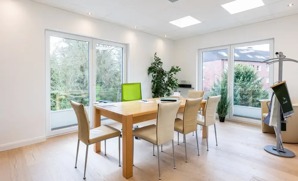 Ein Esszimmer mit Tisch und Stühlen und vielen Fenstern.