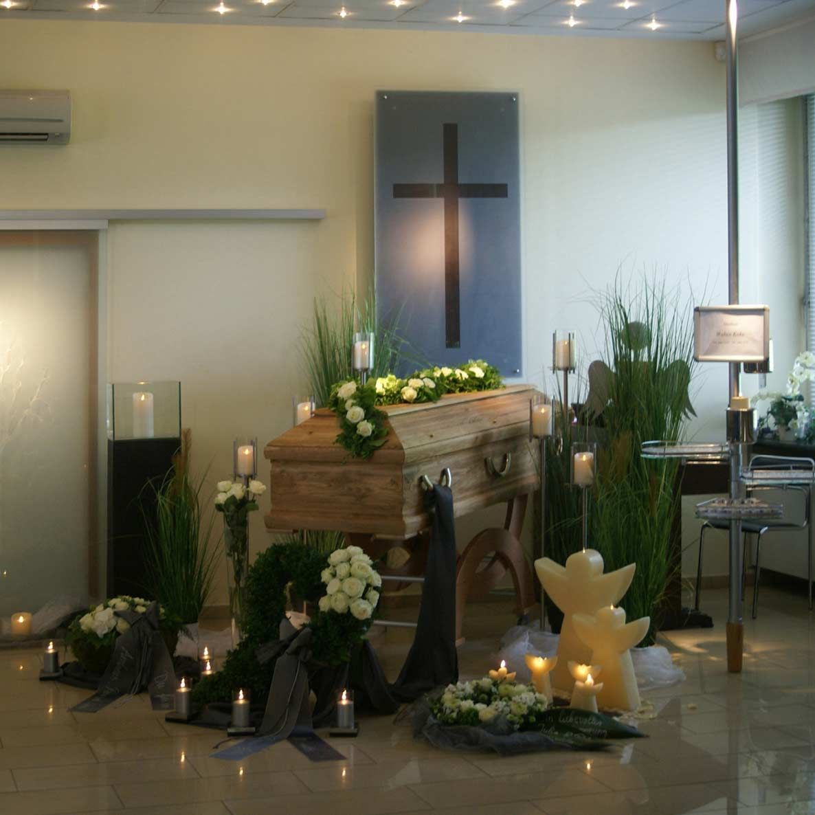 Ein Raum mit einem Sarg, umgeben von Kerzen und Blumen