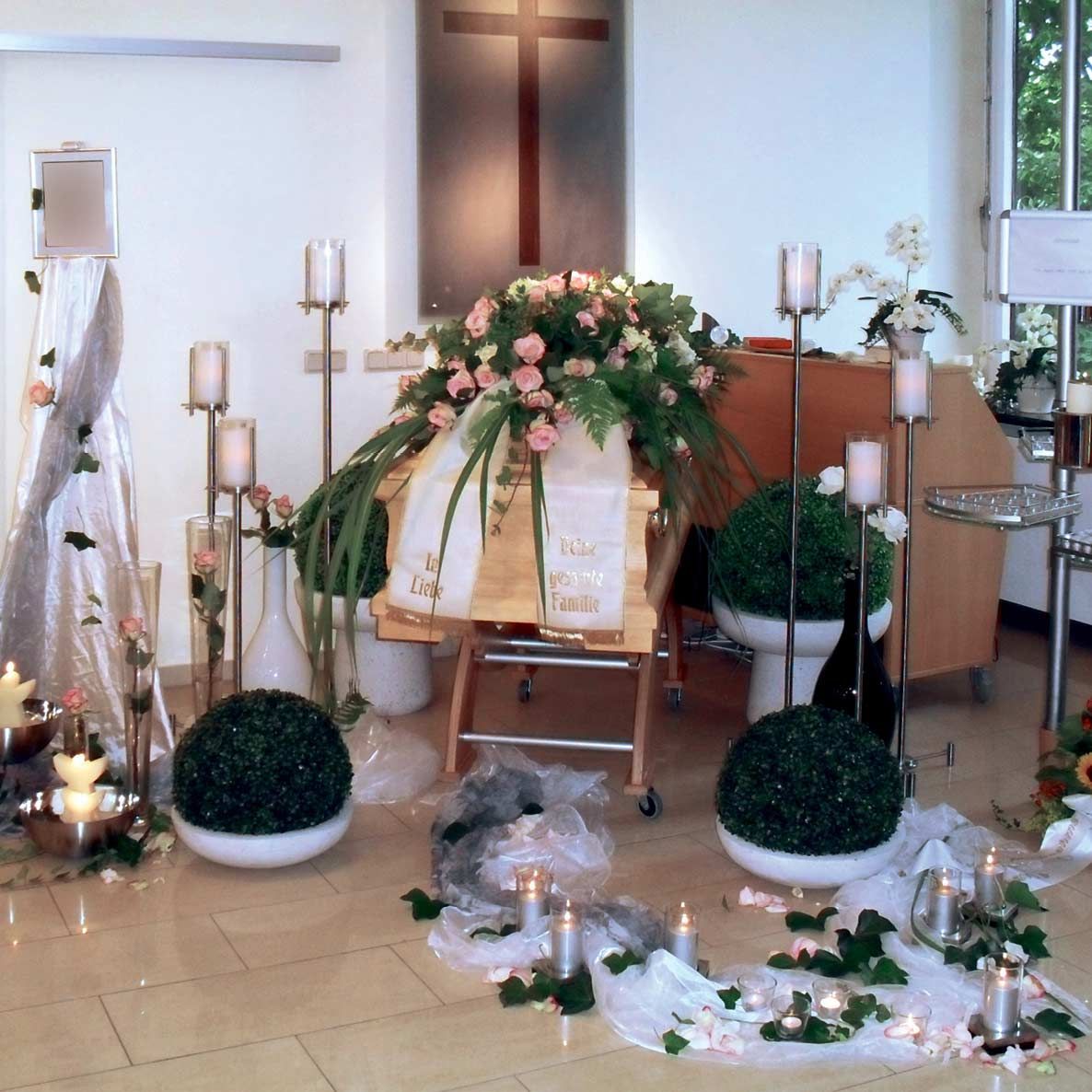 Ein mit Kerzen und Blumen dekorierter Raum mit einem Kreuz im Hintergrund