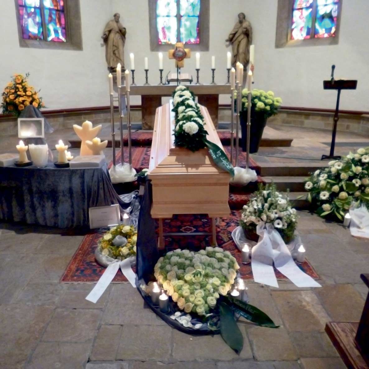 Eine Kirche mit einem Sarg, umgeben von Blumen und Kerzen