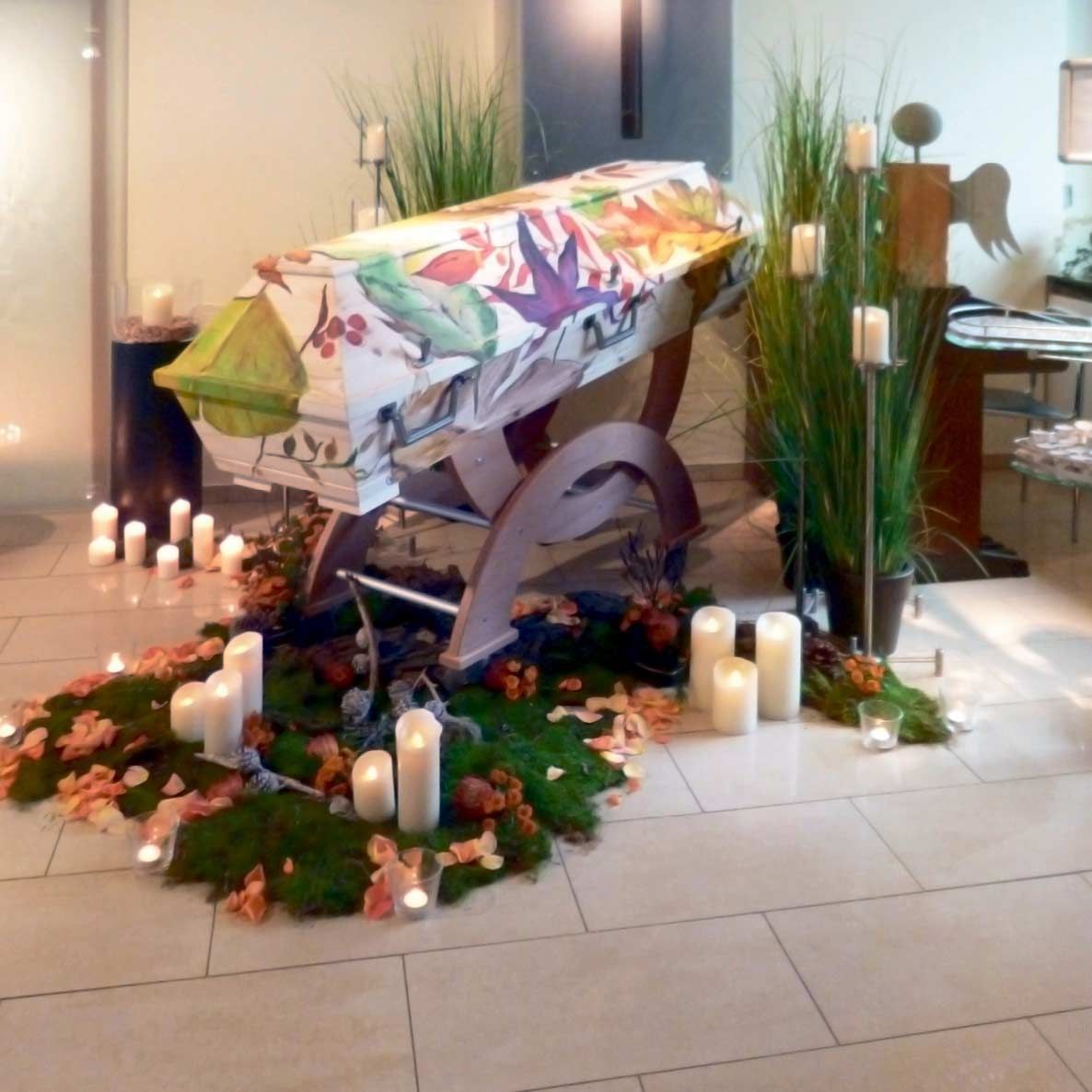 Ein Sarg ist mit Blumen und Kerzen in einem Raum dekoriert