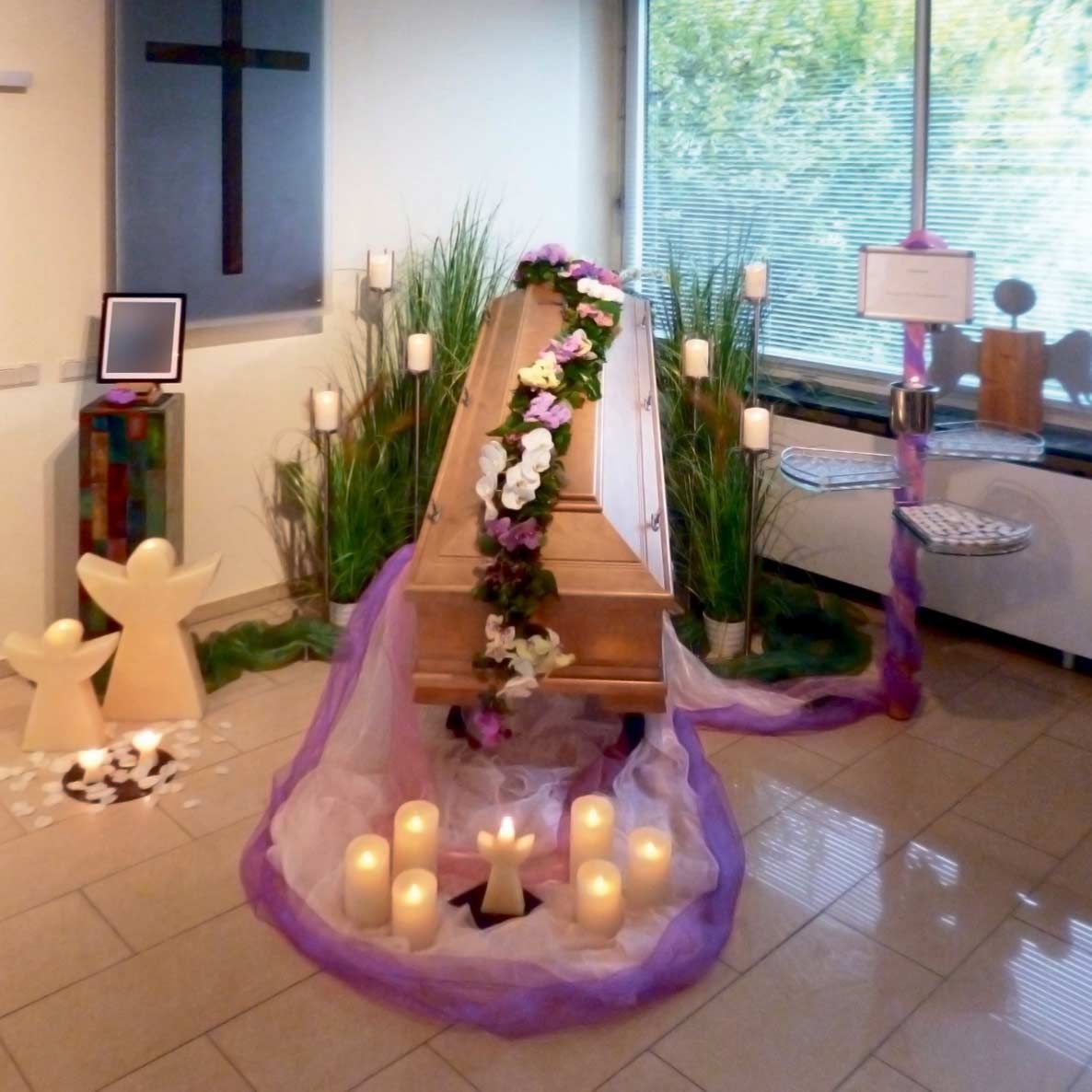 Ein Raum mit einem Sarg, umgeben von Kerzen und Blumen