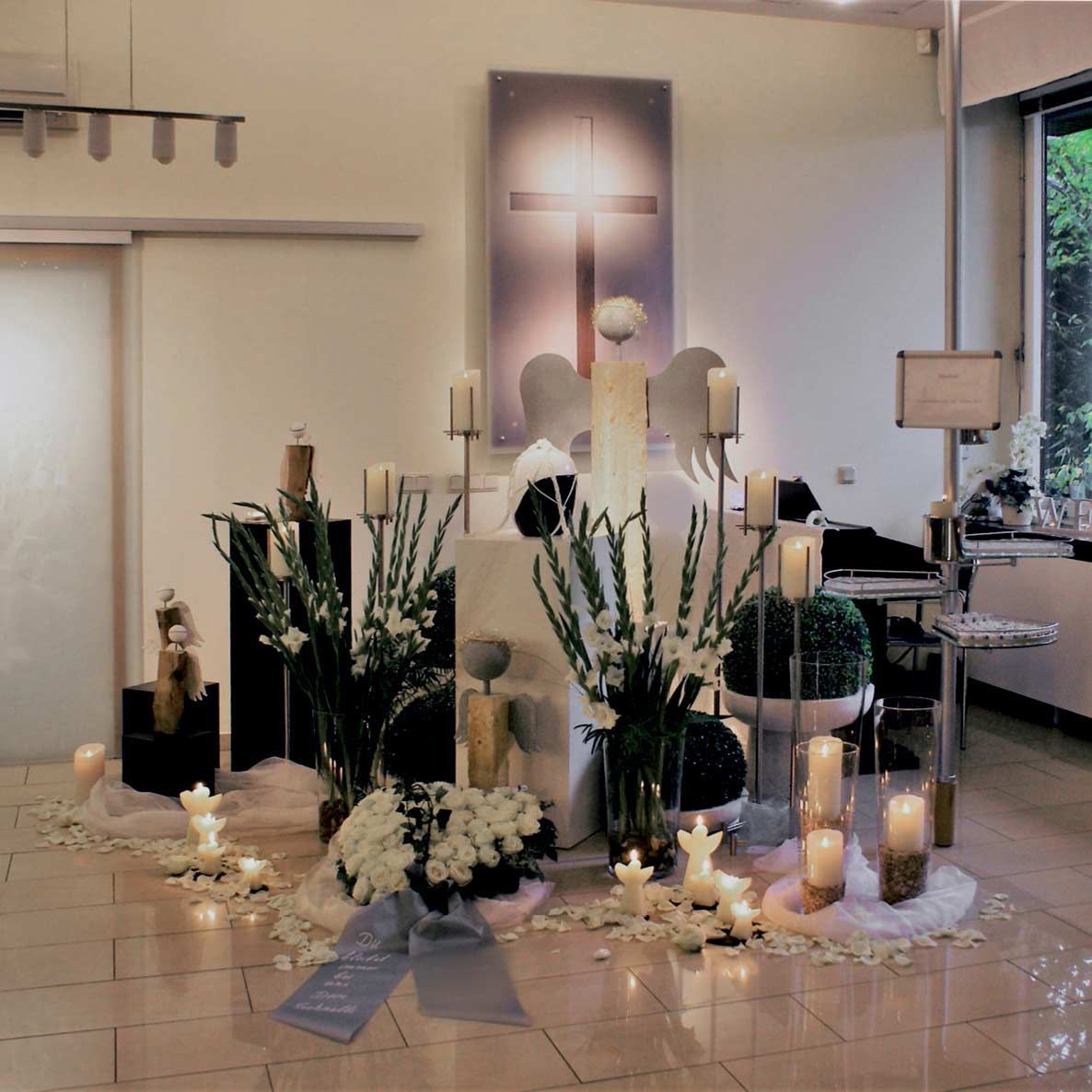 Ein Zimmer mit Kerzen, Blumen und einem Kreuz an der Wand