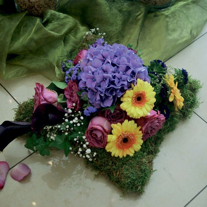 Ein Strauß violetter und gelber Blumen liegt auf dem Boden