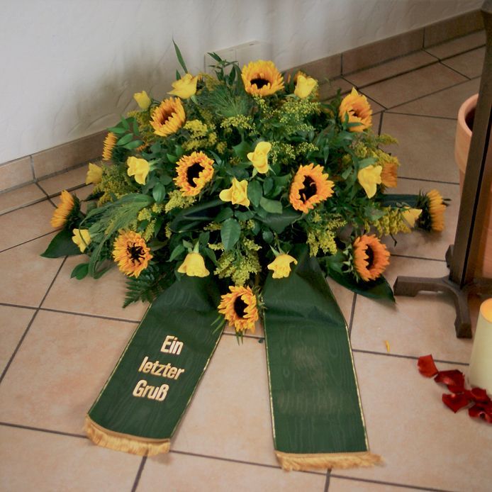 Ein Blumenstrauß mit einer grünen Schleife mit der Aufschrift „Ein letzter Gruß“