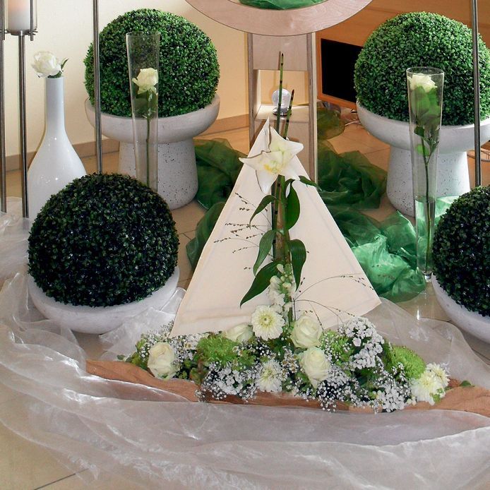 Ein Boot aus Blumen und Grünpflanzen steht auf einem Tisch