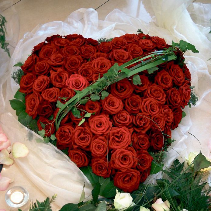 Ein herzförmiger Strauß roter Rosen und Grün