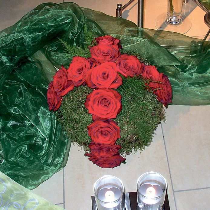 Ein Strauß roter Rosen, umgeben von Grün und Kerzen