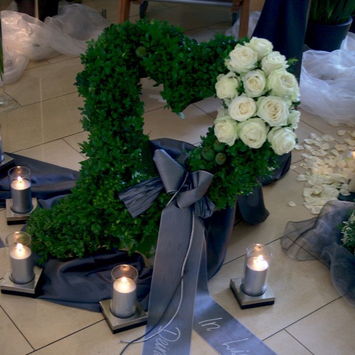 Ein Kranz in Herzform ist von Kerzen umgeben