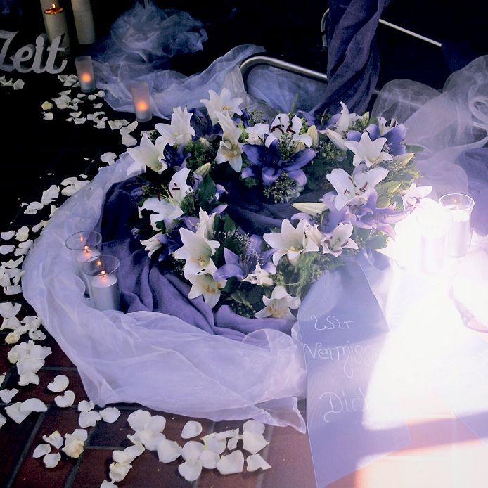 Ein Blumenkranz ist von Blütenblättern und einem Schild mit der Aufschrift Zelt umgeben.