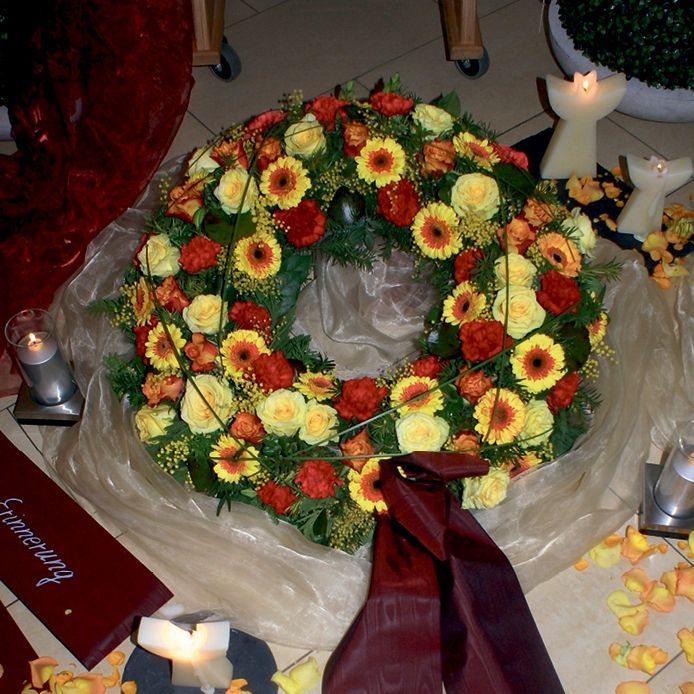 Ein Kranz aus gelben und roten Blumen steht auf einem Tisch