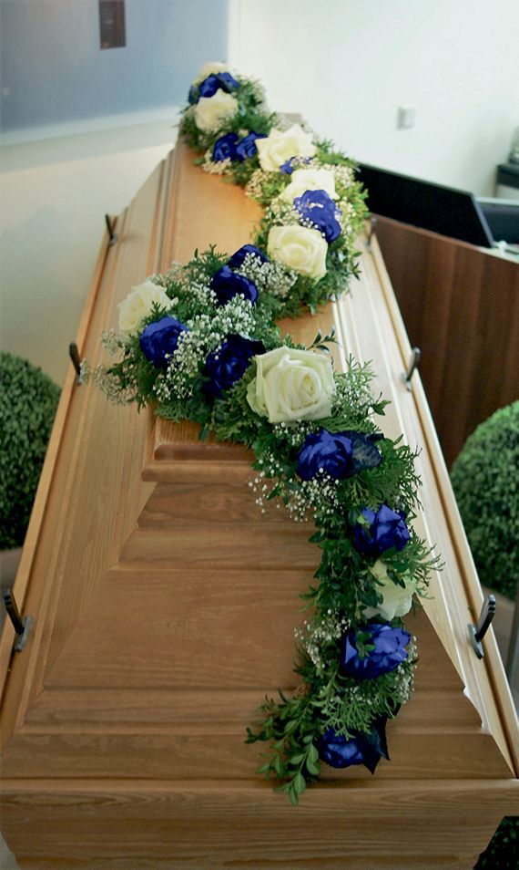 Ein Holzsarg mit blauen und weißen Blumen darauf.