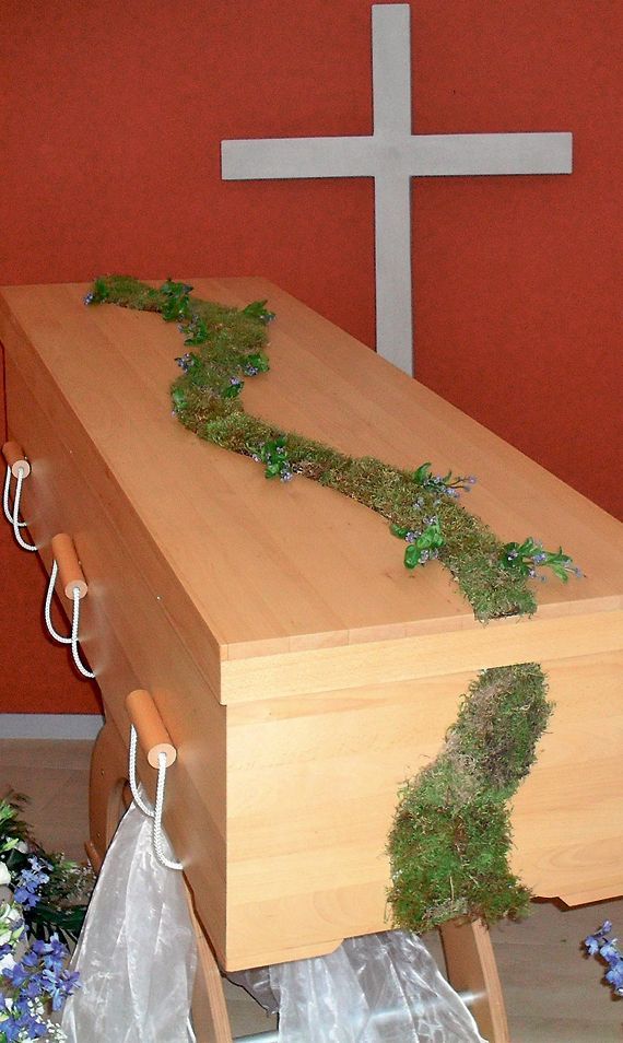 Ein Holzsarg mit einem Kreuz im Hintergrund