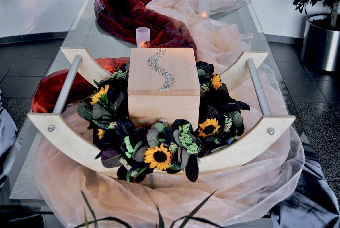 Ein hölzerner Schaukelstuhl mit Blumen und einer Kerze darin