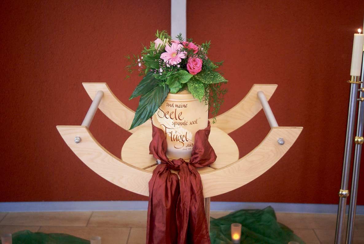 Eine Holzskulptur mit Blumen und Kerzen darauf.