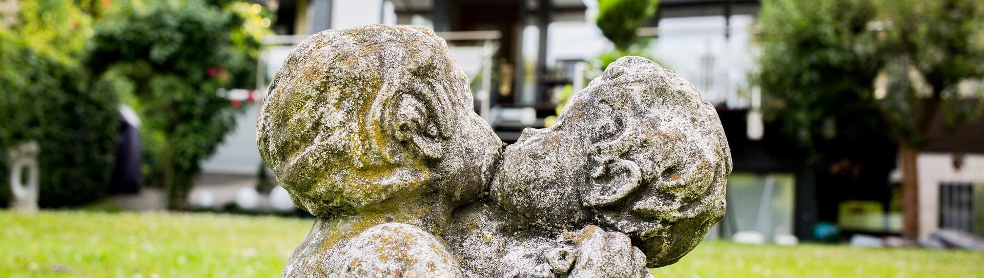 Eine Nahaufnahme einer Statue von zwei sich küssenden Engeln in einem Garten.