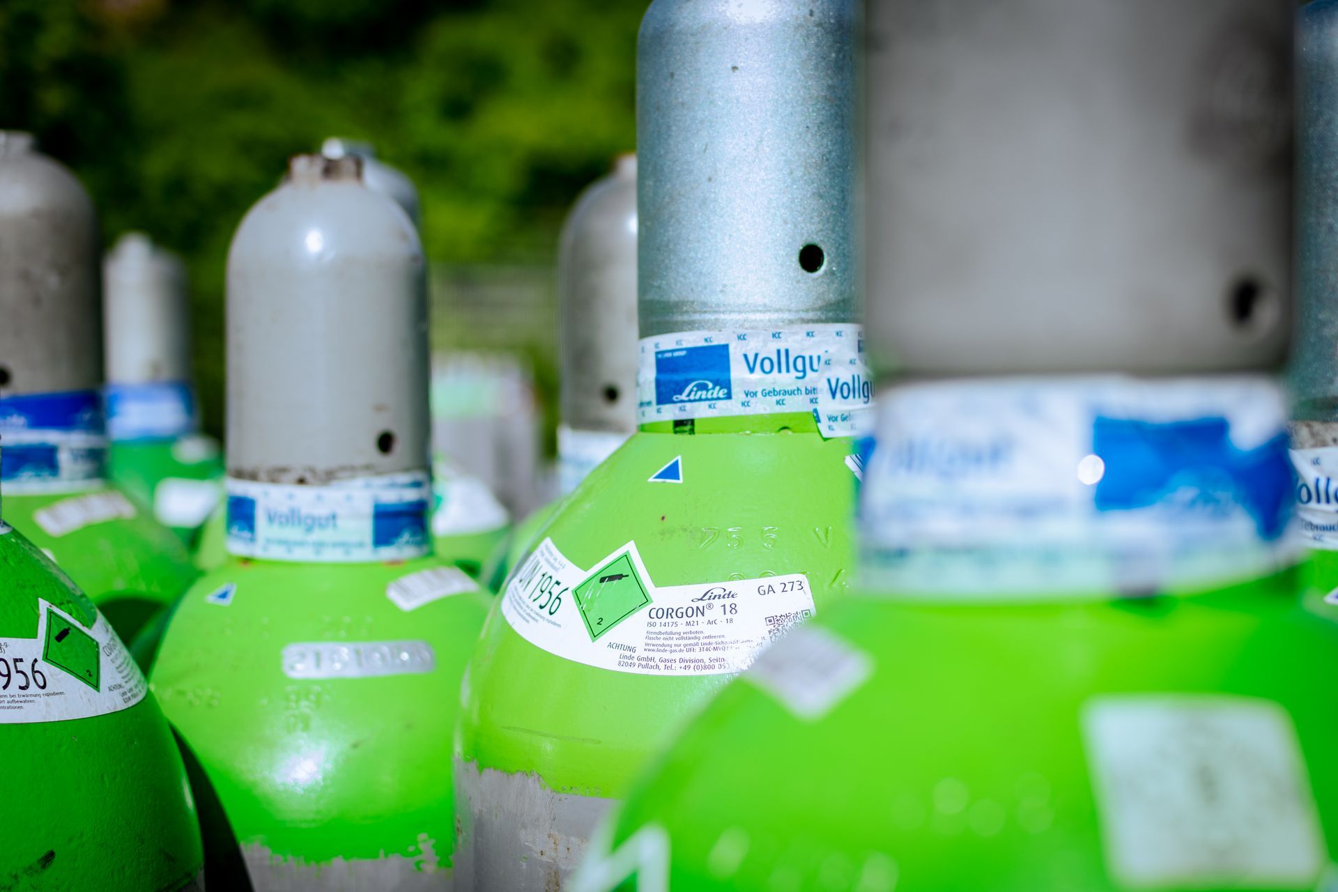 Ein Schweißer arbeitet mit hellen Funken und blau-orangefarbenem Licht an Metall in einer dunklen Werkstatt.