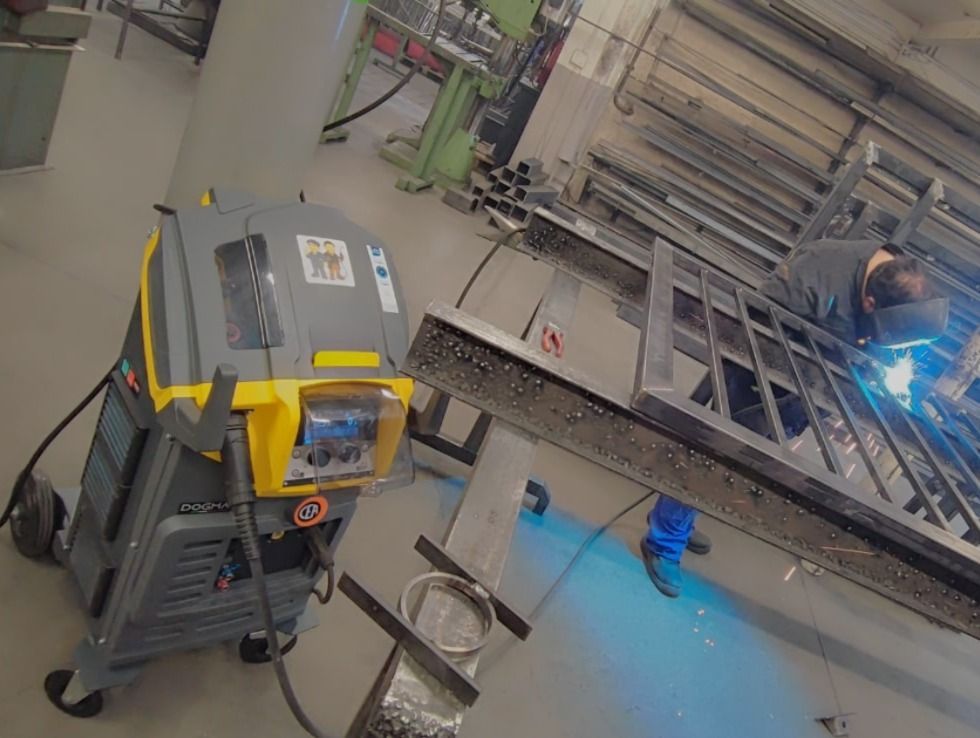 Schweißfunken, leuchtend blau und orange, in einer dunklen Industrieumgebung.