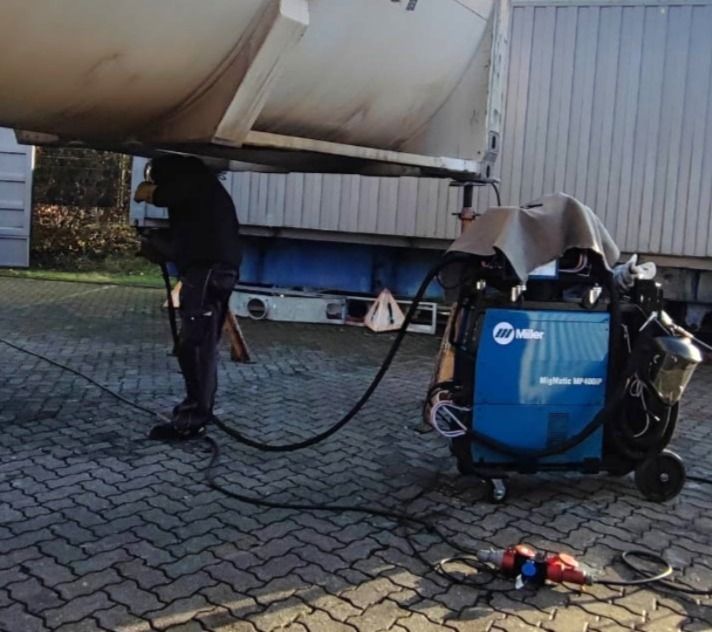 Eine Person schweißt Metall mit Funken und hellblauem Licht.