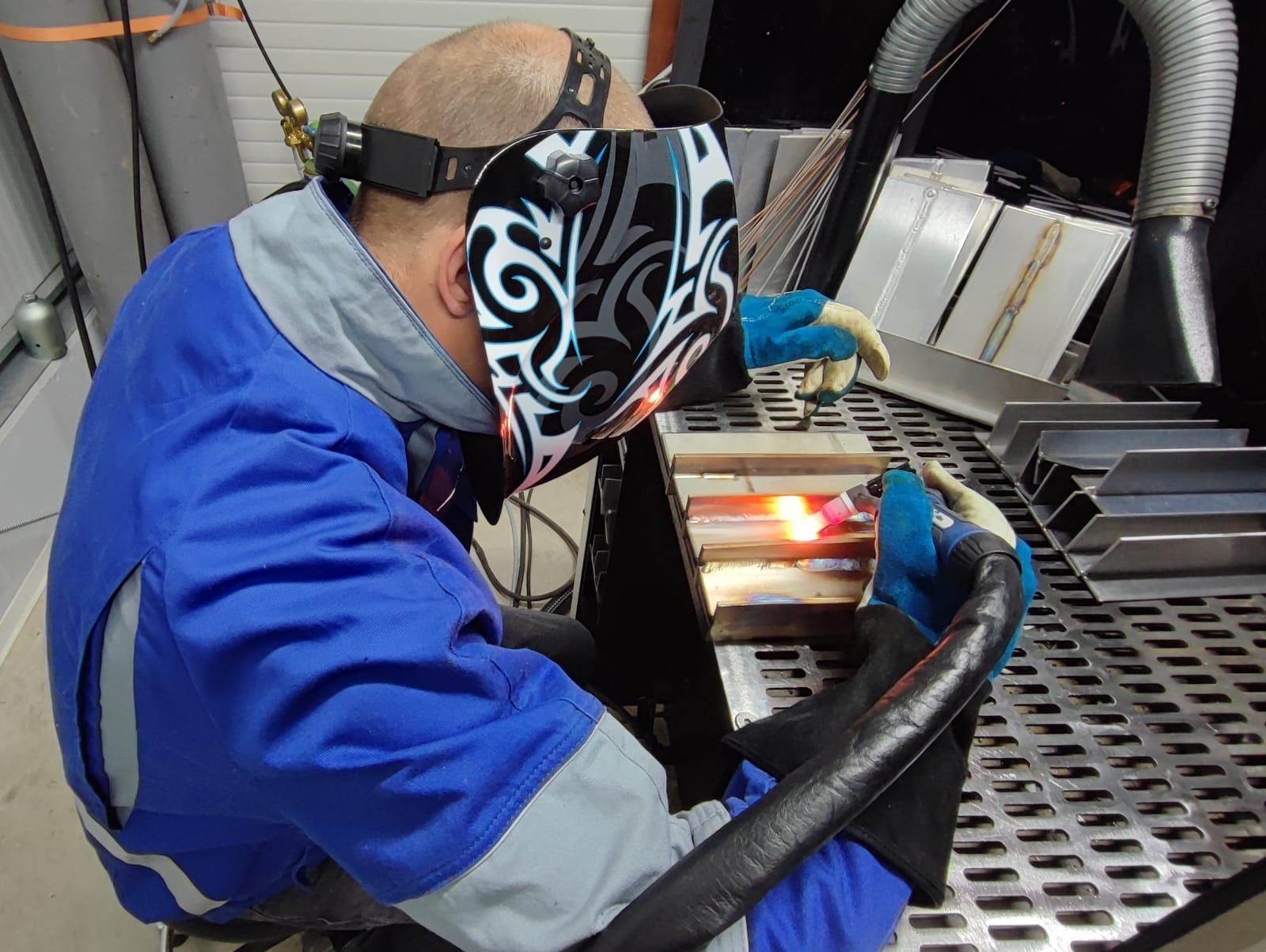 Schweißer bei der Arbeit, schweißt Metall mit hellen Funken und blauem Licht in einer Werkstatt.
