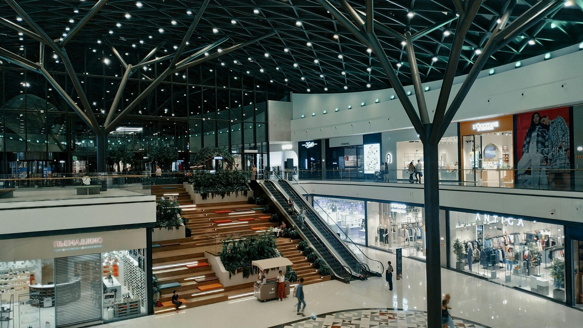 Centro comercial moderno cubierto con escaleras mecánicas, escaparates de cristal 
