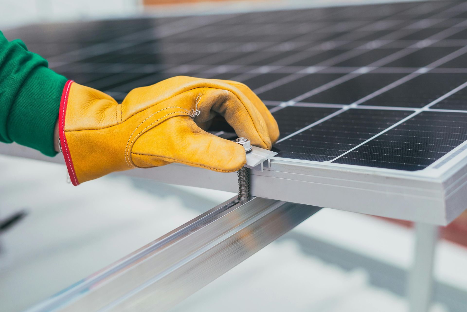 Una mano enguantada ajusta el marco de un panel solar en una instalación en el tejado.