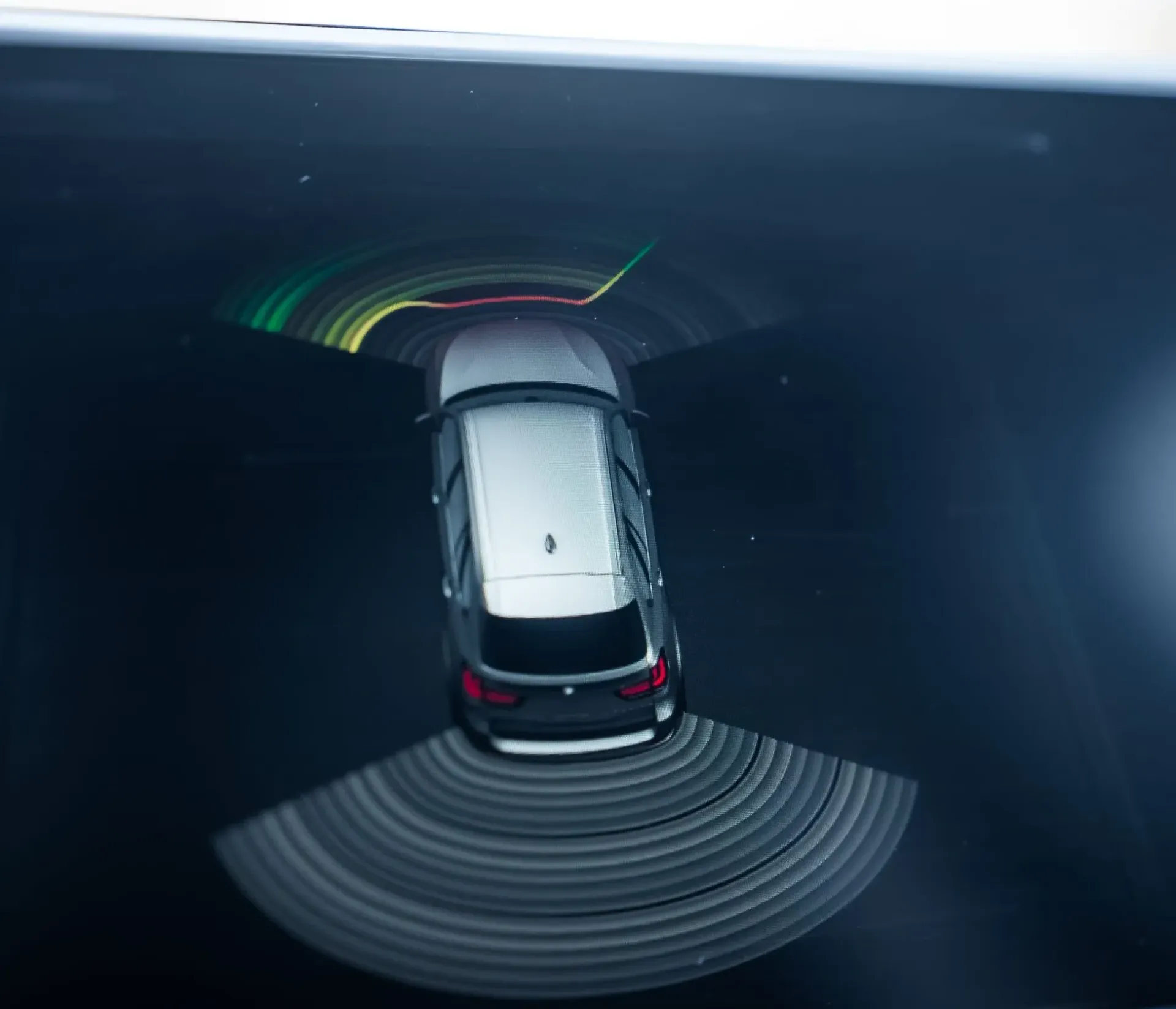 Un coche circulando por un túnel oscuro con reflejos brillantes de los faros y marcas viales.