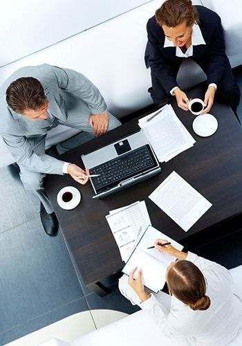 Un grupo de personas están sentadas alrededor de una mesa con papeles y una computadora portátil.