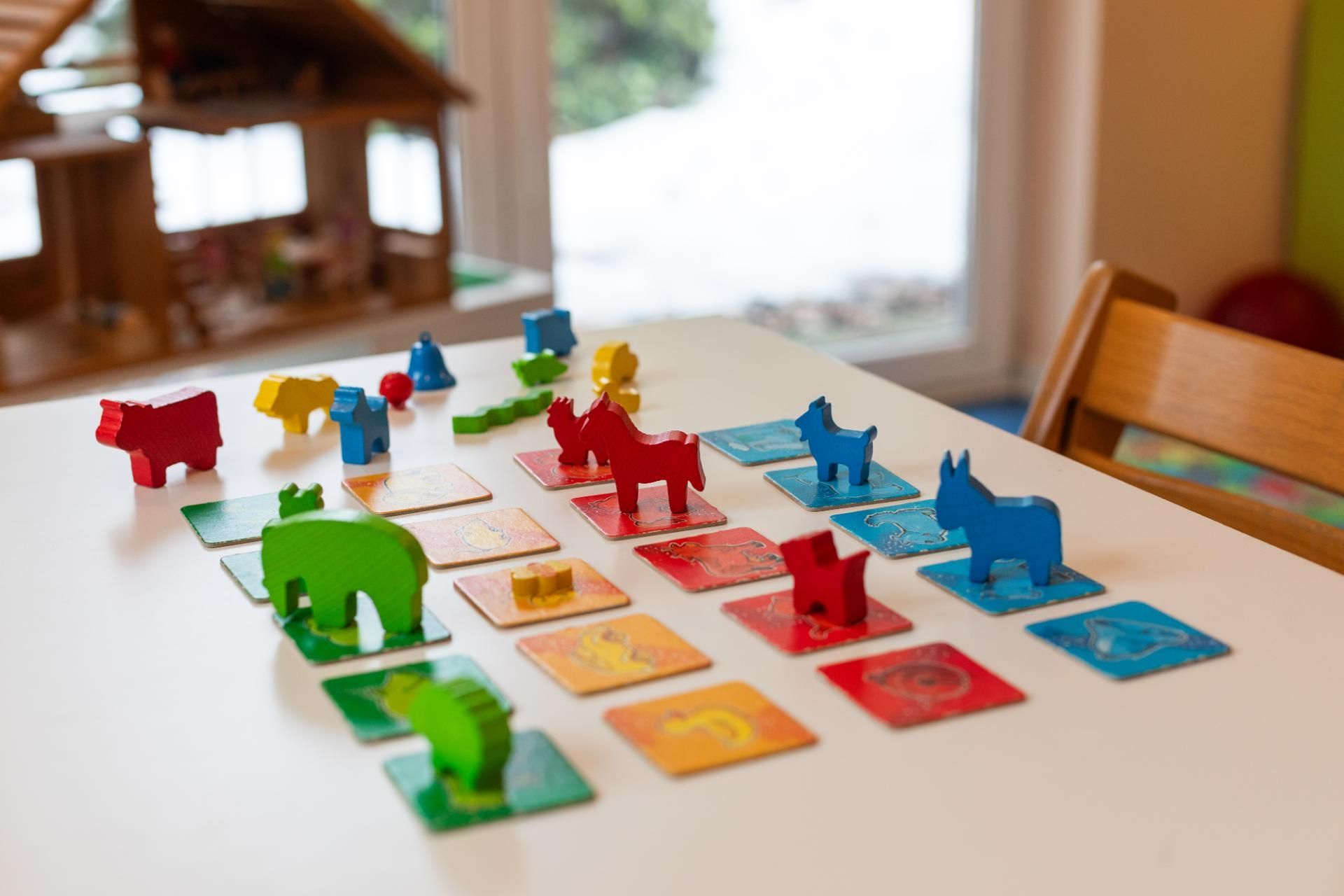Bunte Tierfiguren und Spielsteine sind auf einem Tisch zu einem Brettspielaufbau angeordnet.