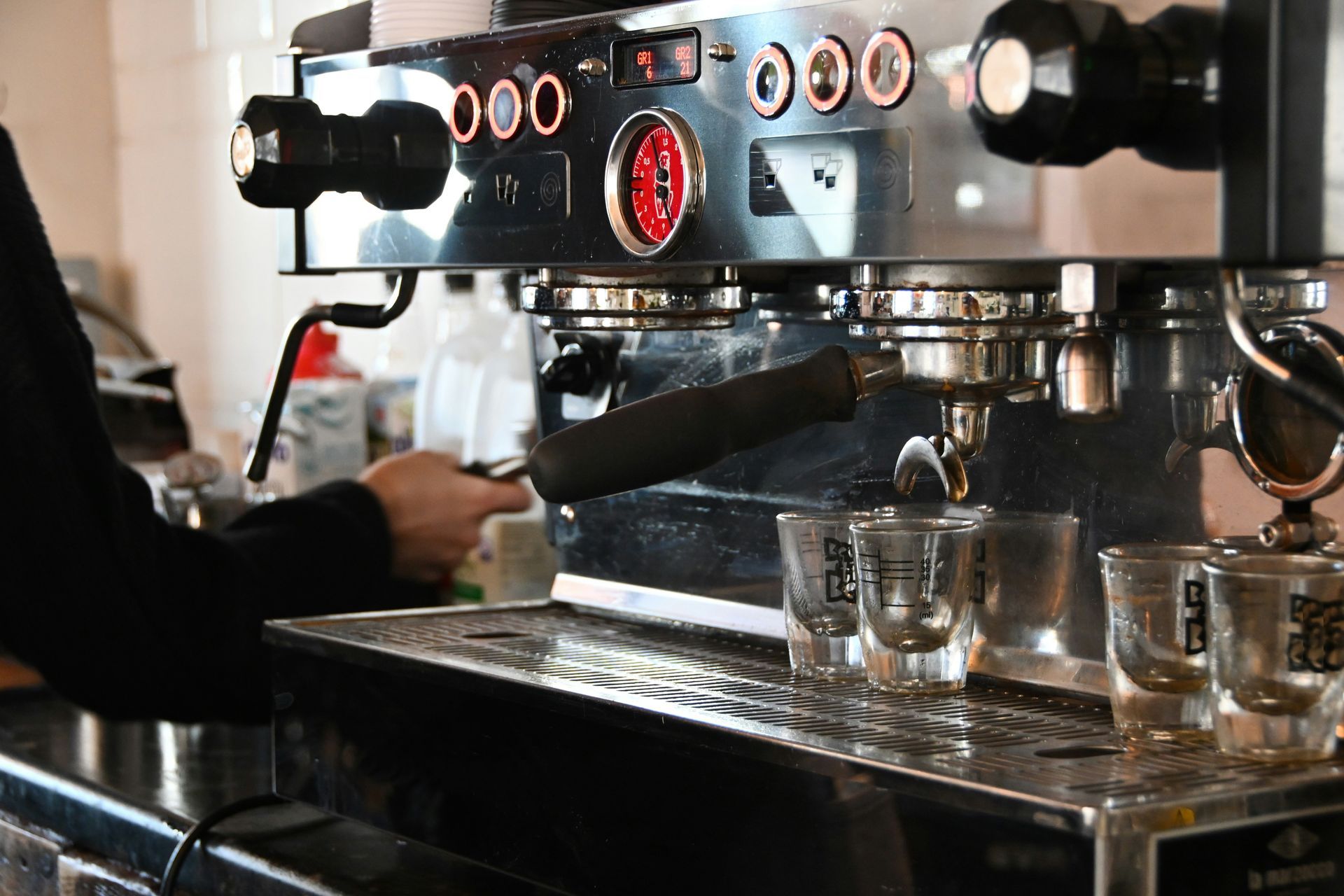 Máquina de café expreso que dispensa café en vasos pequeños sobre un mostrador.