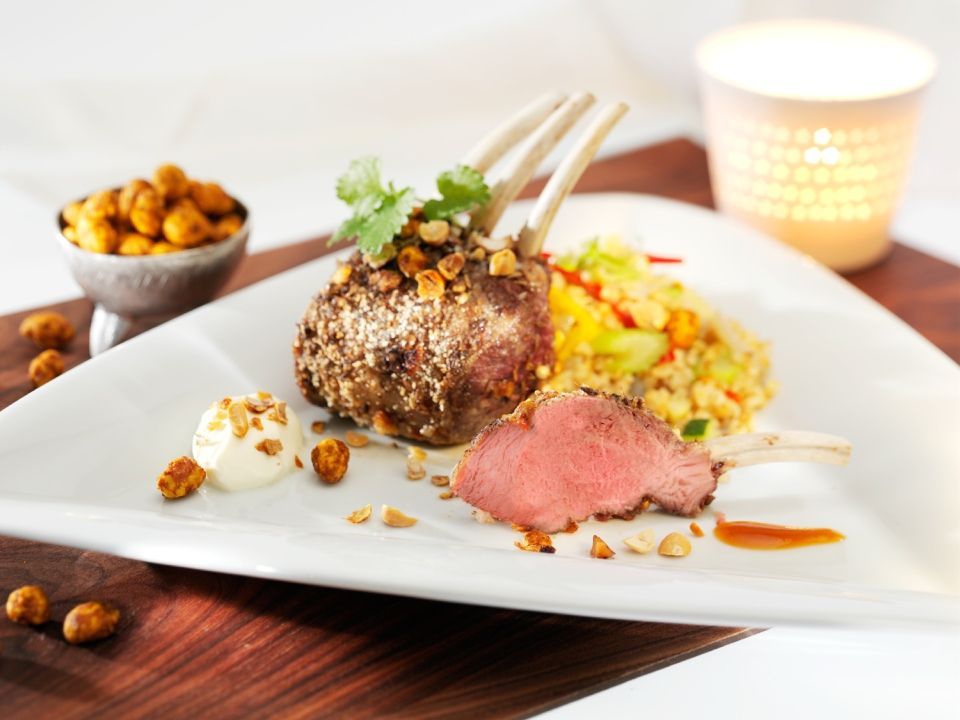 Lammkotelett mit Couscous und Kichererbsen, auf einem weissen Teller mit einer brennenden Kerze.