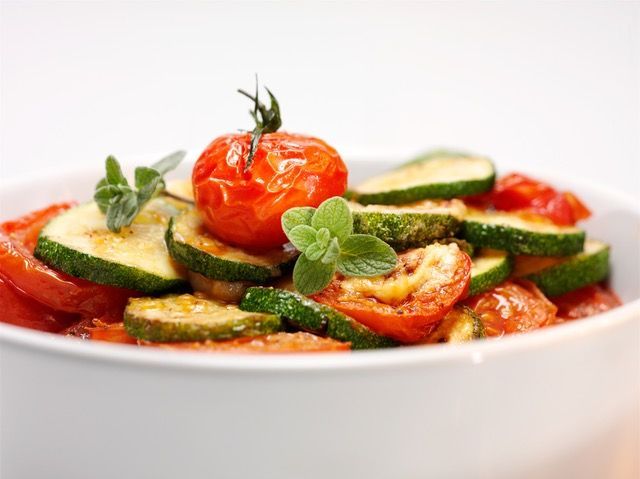 Weisser Teller mit Oktopus, Linsen, Kräutern und einer kleinen Schüssel Sosse.