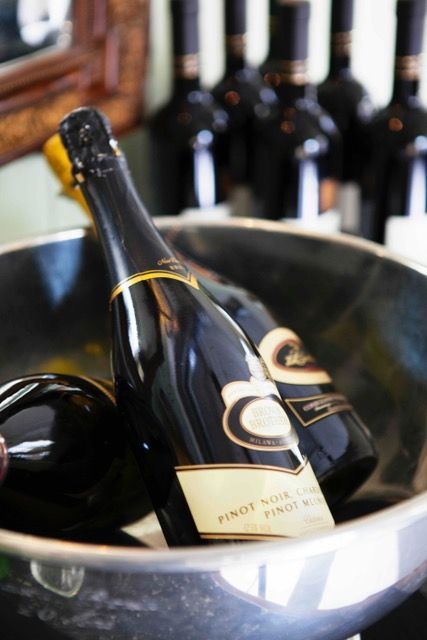 Öl wird von Hand aus einer Flasche in einen Messbecher gegossen; im Hintergrund sind Zitronenhälften zu sehen.