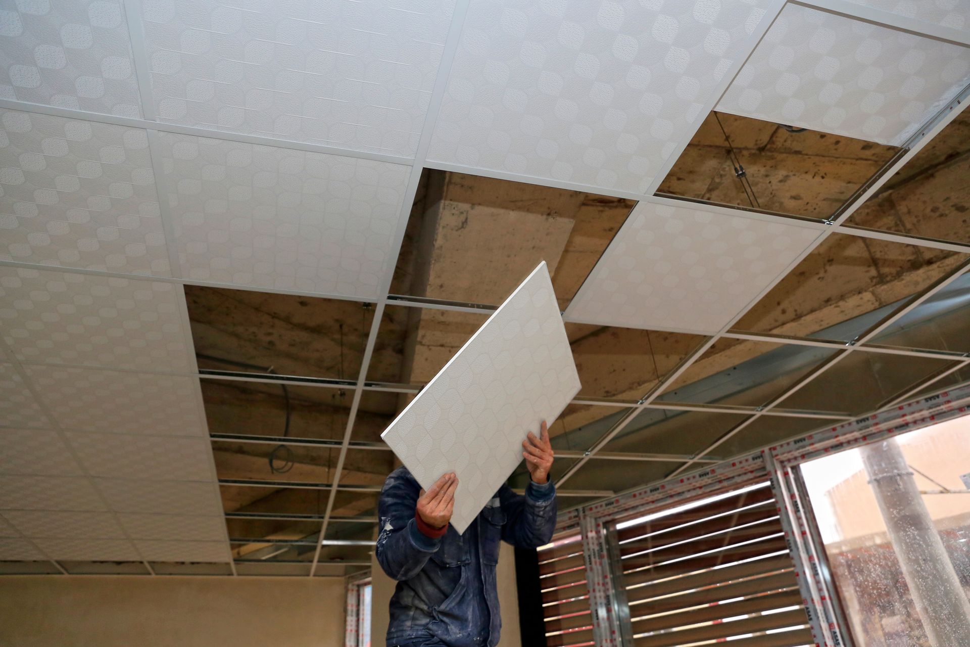 Personne installant une dalle de plafond.