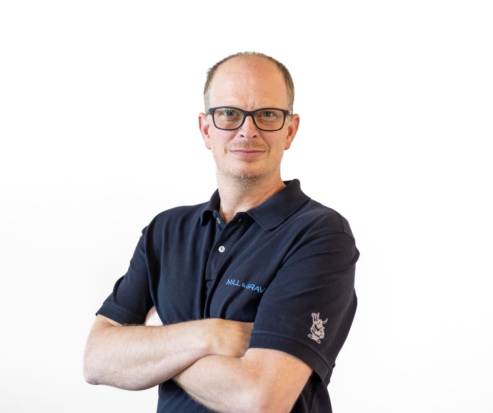 Ein Mann mit Brille und schwarzem Hemd steht mit verschränkten Armen da.