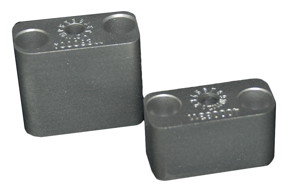 Zwei Metallstücke liegen nebeneinander auf einer weißen Oberfläche