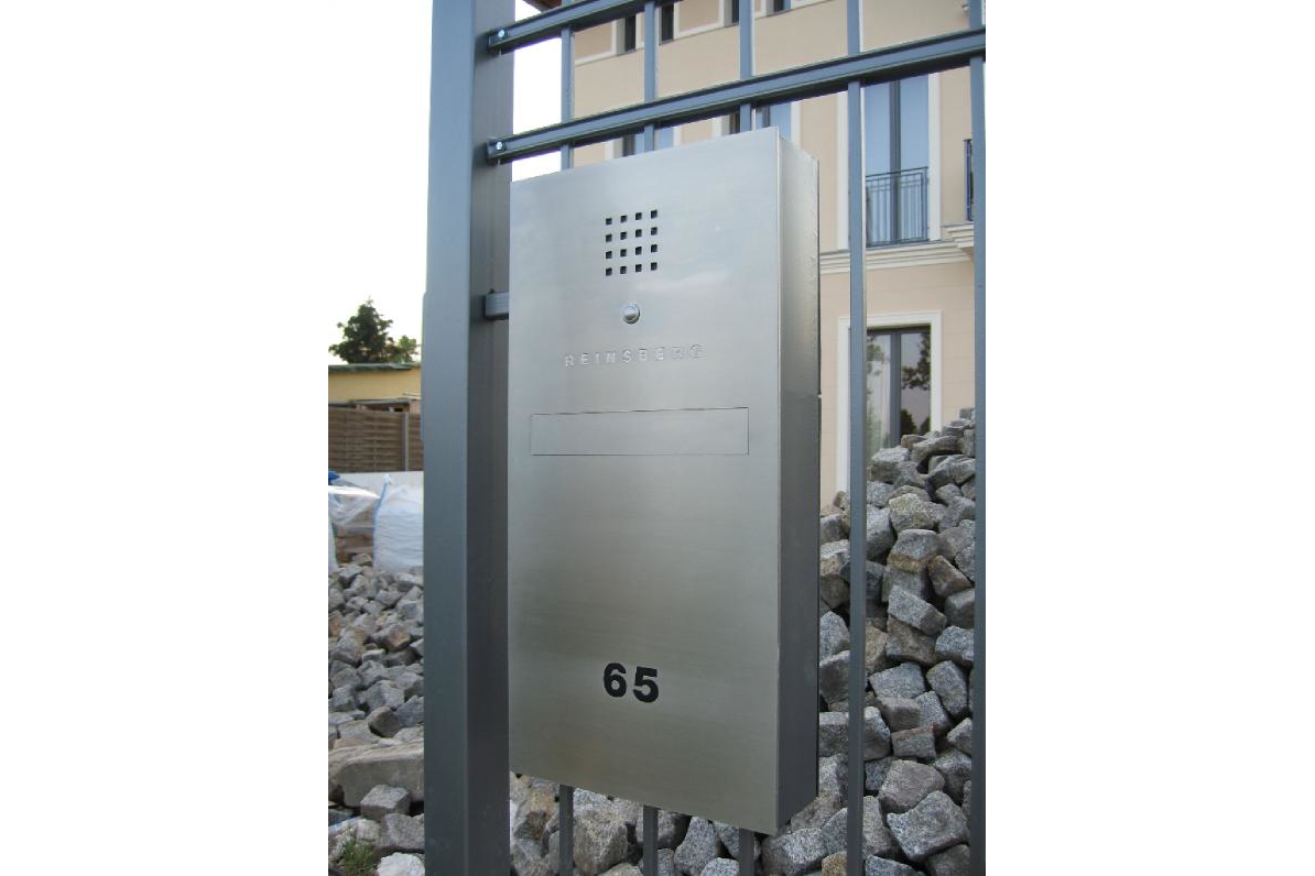 Ein Briefkasten aus Edelstahl mit der Nummer 65 darauf