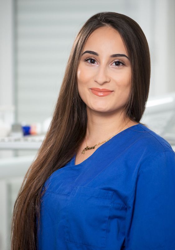 Eine Frau mit langen Haaren trägt einen blauen Kasack.