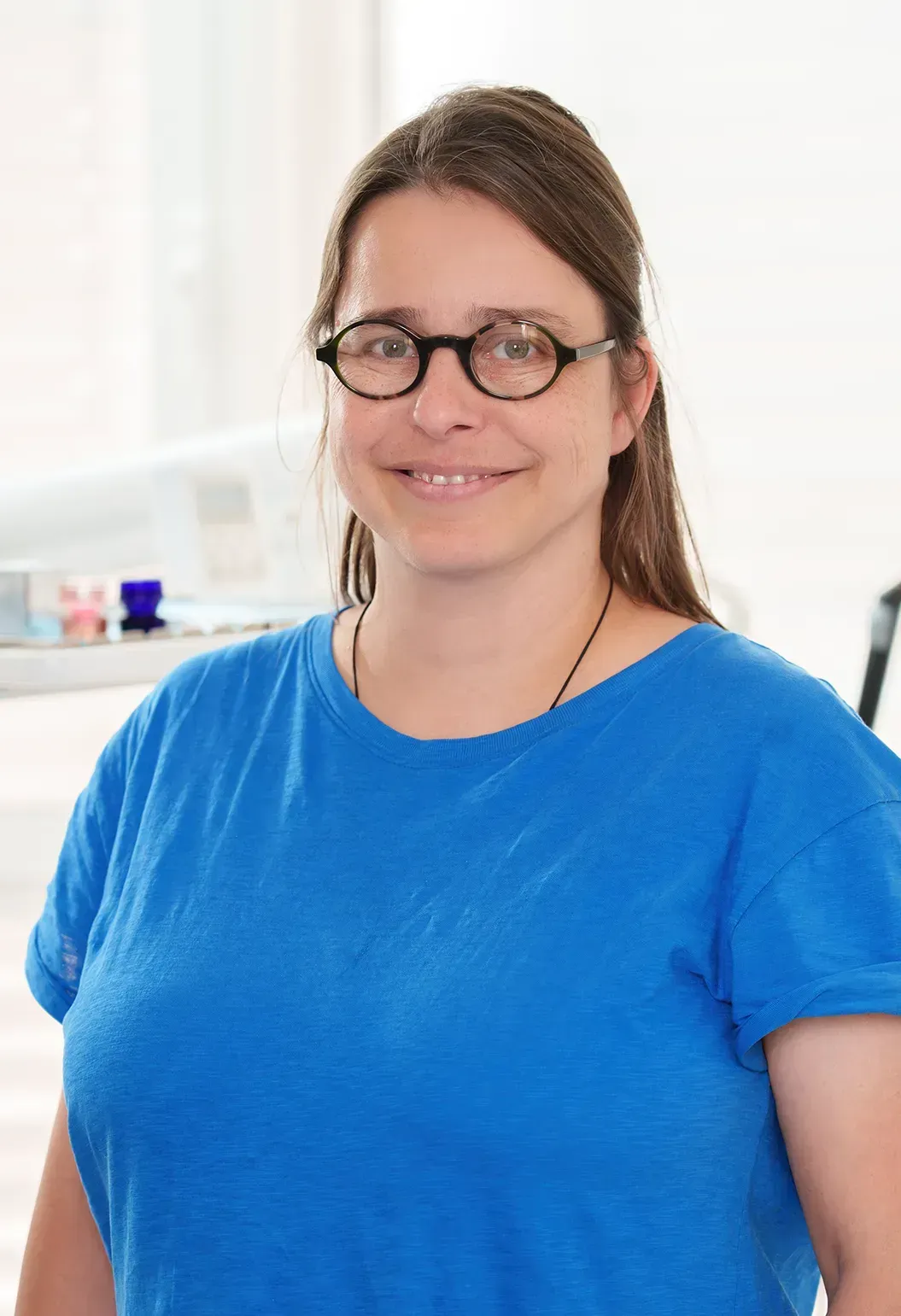 Frau mit Brille in blauem Hemd; Inneneinstellung.