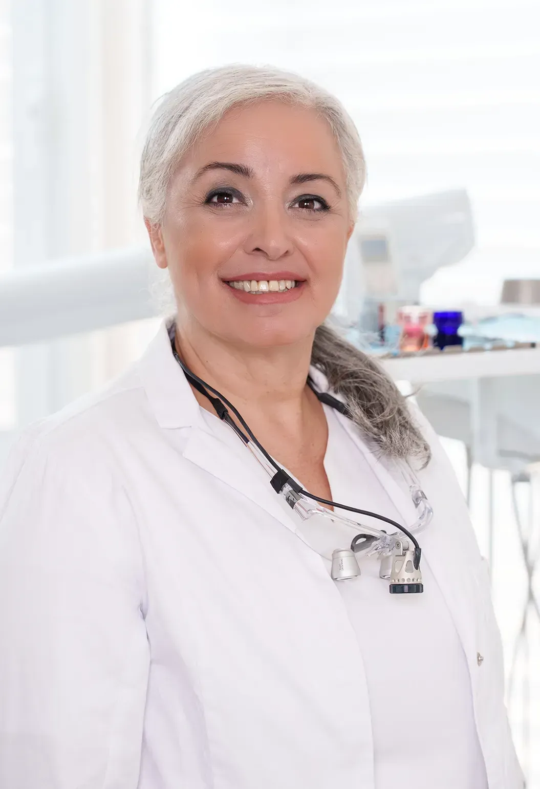 Eine Frau in einem weißen Hemd lächelt in die Kamera.