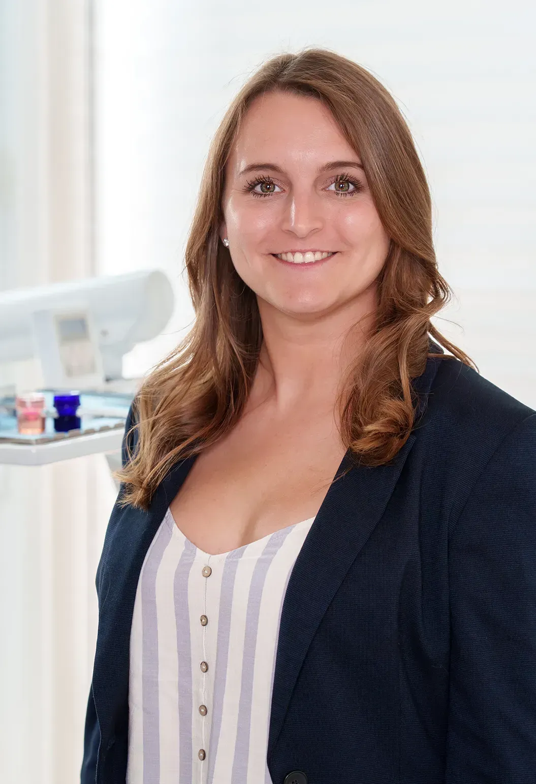 Eine Frau in einer blauen Jacke und einem weißen Hemd lächelt in die Kamera.