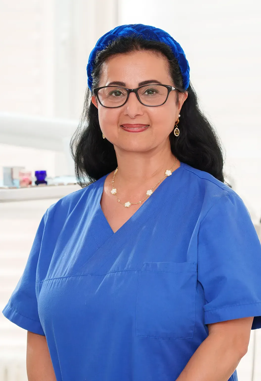 Eine Frau im blauen OP-Kittel lächelt in die Kamera.