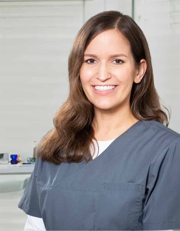 Eine Frau im Kasack lächelt in die Kamera.