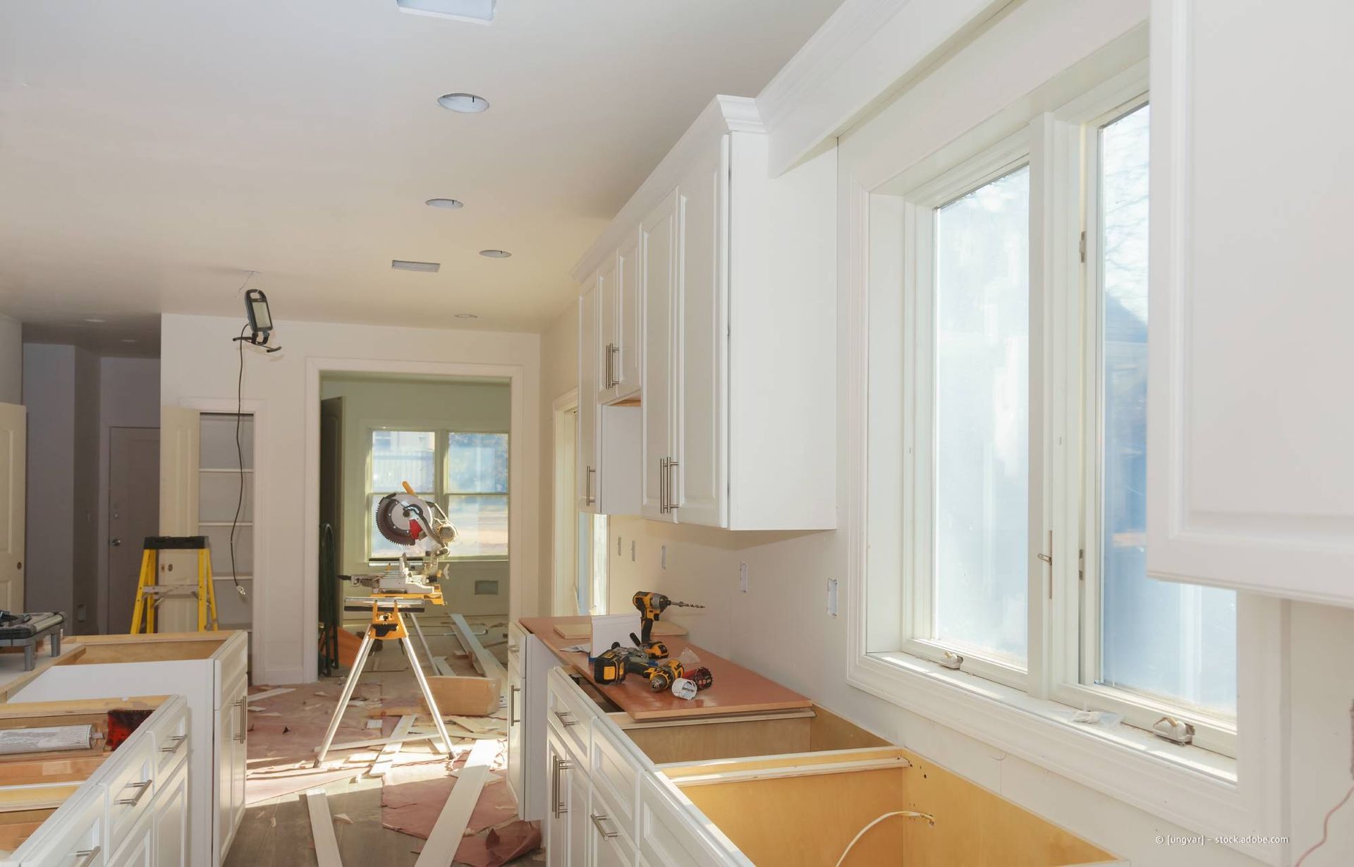 Küche im Umbau mit weißen Schränken, offenen Schubladen und Küchenutensilien.