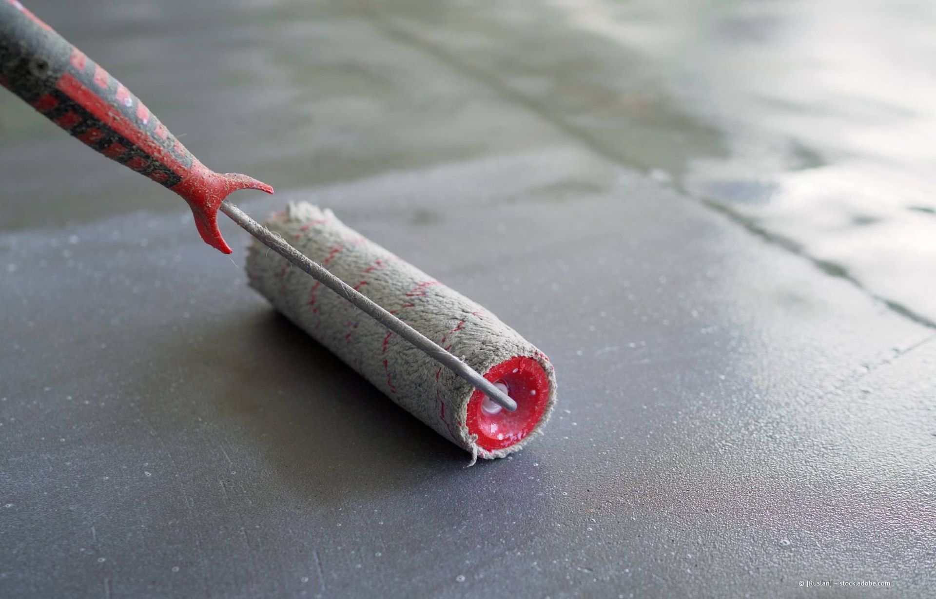 Farbrolle zum Auftragen von silberner Farbe auf einen Boden.