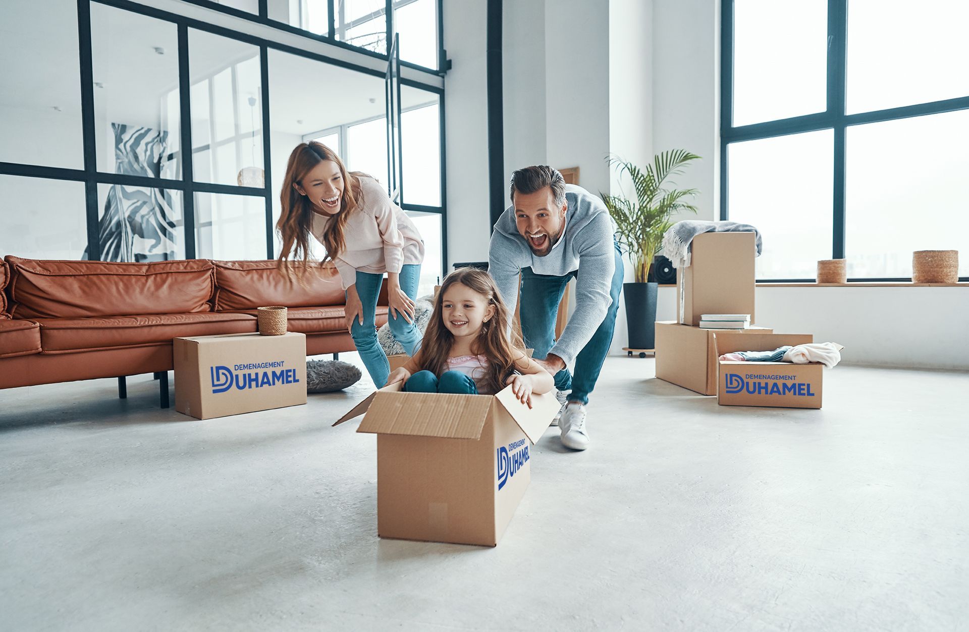 Parents souriants poussant leur fille dans un carton